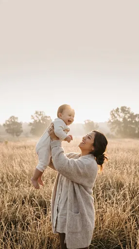 Mother Lifting Laughing Baby in Meadow