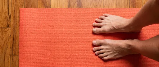 Bare Feet Standing on Coral Yoga Mat