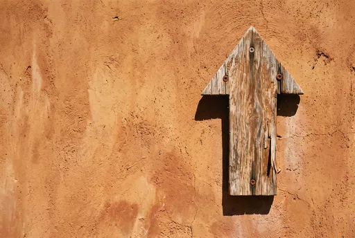 Weathered Wooden Upward Arrow on Terracotta Wall