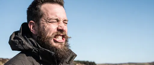 Bearded Man Grimacing Against Blue Sky