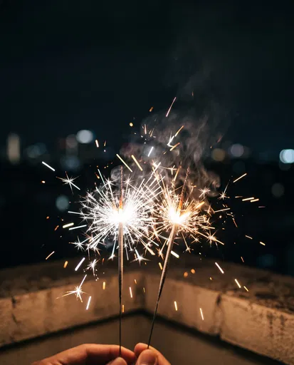 Two Lit Sparklers on Night Rooftop