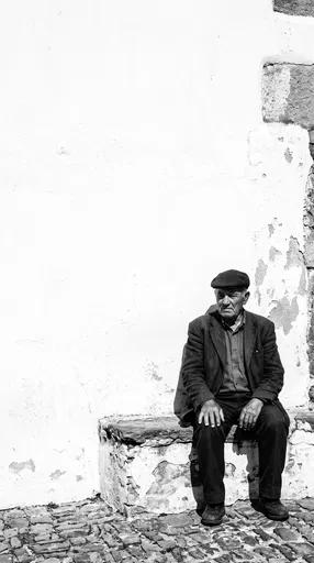 Senior Man Sitting Against White Wall