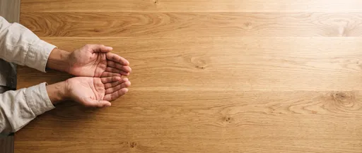 Cupped Hands Over Wooden Table