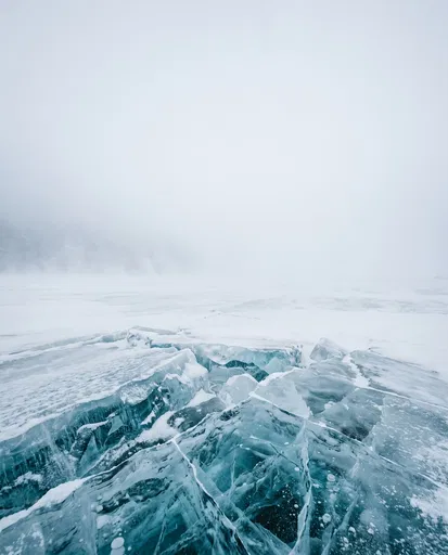 Cracked Blue Ice in Foggy Winter Landscape