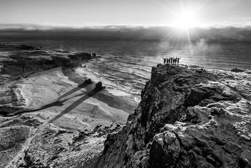 Friends Celebrating Sunrise on Coastal Cliff