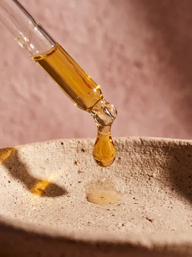Glass Pipette Dropping Oil Over Ceramic Dish
