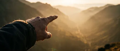 Hiker Hand Pointing at Golden Mountains