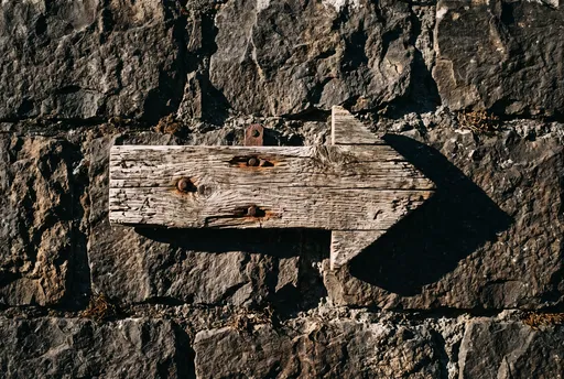 Weathered Wooden Arrow on Stone Wall