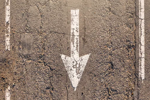 Weathered White Downward Arrow on Asphalt
