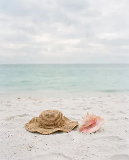 Straw Hat and Conch Shell on Beach