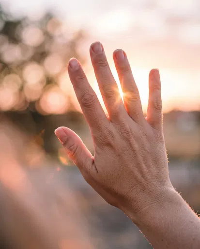 Hand Raised Toward Golden Hour Sunset