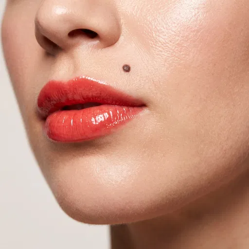 Close-Up of Coral Glossy Lips and Beauty Mark