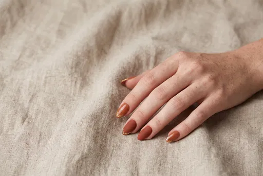 Freckled Hand With Autumn Manicure on Linen