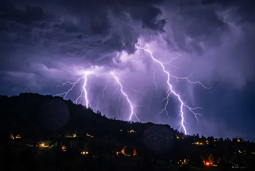 Purple Lightning Bolts Behind Dark Hillside