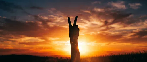 Silhouetted Hand Making Peace Sign at Sunset