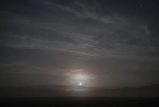 Hazy Crescent Moon Over Misty Horizon
