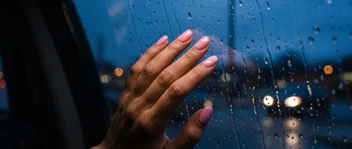 Hand With Pink Nails on Rainy Window