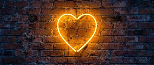 Glowing Amber Neon Heart on Brick Wall
