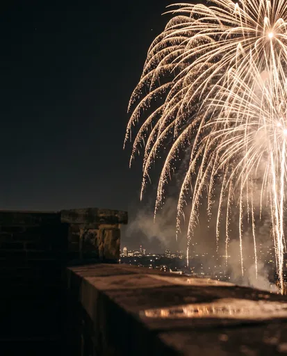 Golden Fireworks Over Rooftop Ledge
