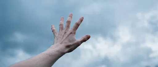 Wet Hand Reaching Into Overcast Sky