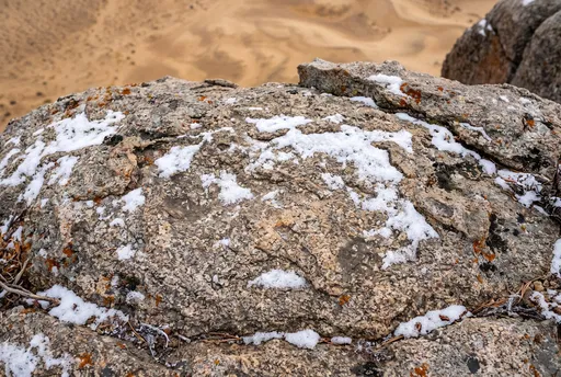 Snow-Dusted Boulder Overlooking Desert Dunes