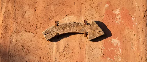 Rustic Wooden Arrow on Adobe Wall