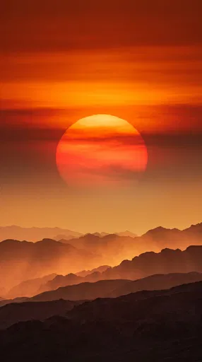 Large Orange Sun Over Layered Mountains