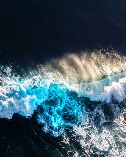 Aerial Bioluminescent Wave Crashing in Dark Ocean