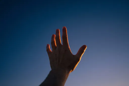Hand Reaching Toward Twilight Sky
