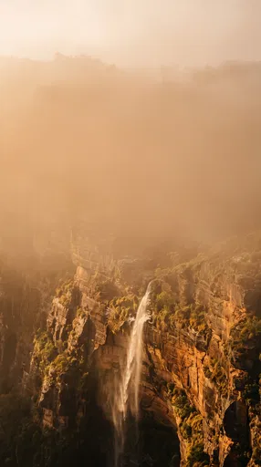 Golden Waterfall on Misty Sandstone Cliff