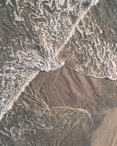 Aerial View of Ocean Surf on Sand