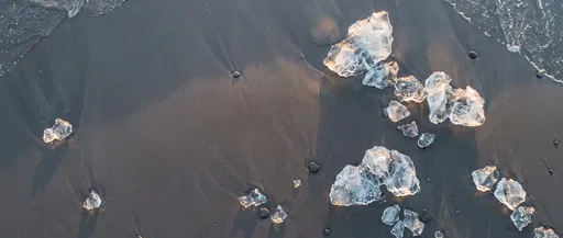 Glacial Ice Fragments on Wet Grey Sand