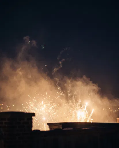 Golden Fireworks Behind Rooftop Ledge