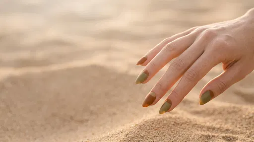 Hand With Earthy Half-Moon Manicure Over Sand