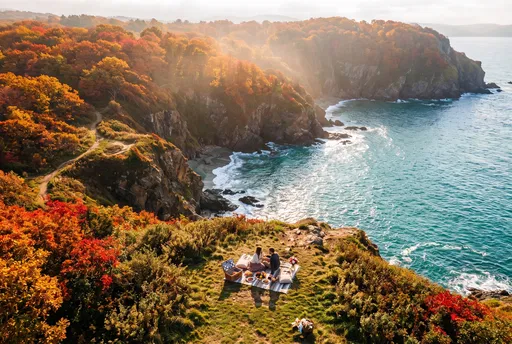 Couple Having Autumn Picnic on Coastal Cliff