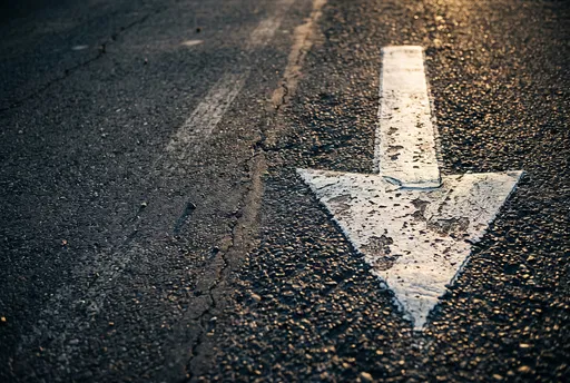 Weathered White Downward Arrow on Asphalt