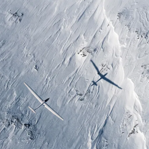 White Sailplane Over Snowy Terrain