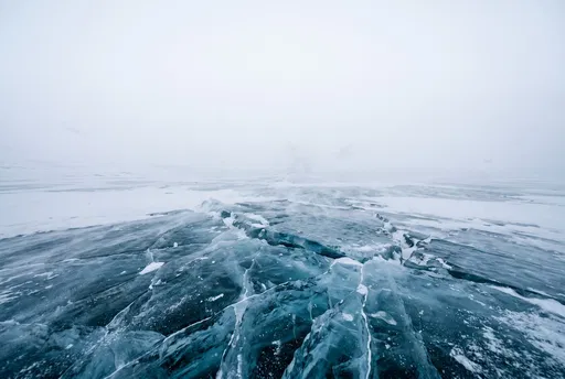 Cracked Blue Ice in Foggy Landscape