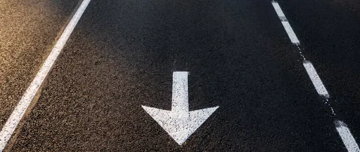 White Down Arrow on Asphalt Road