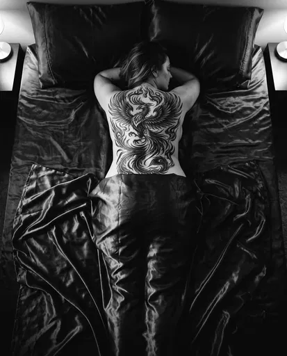 Woman With Phoenix Back Tattoo On Bed