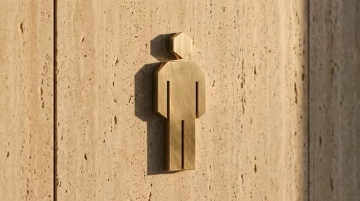 Brushed Brass Male Restroom Sign on Stone