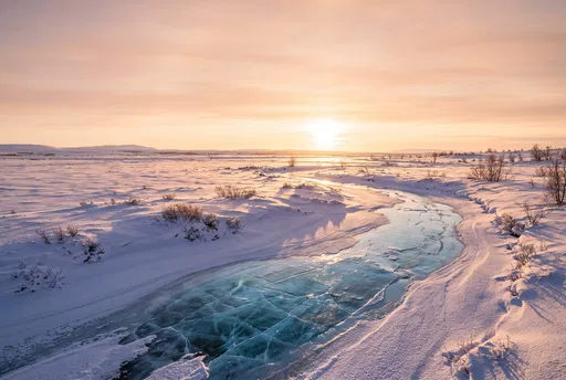 Frozen River Across Snowy Plains at Sunset