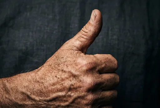 Close-Up of Weathered Hand Giving Thumbs Up