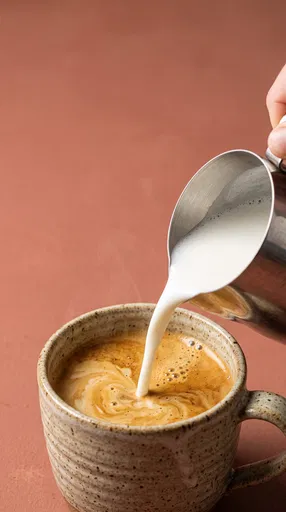 Steamed Milk Pouring Into Espresso Mug