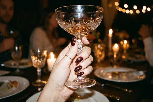 Hand with Burgundy Nails Holding Coupe Glass
