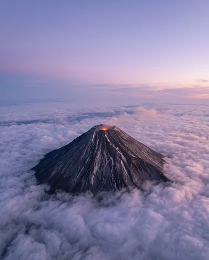Glowing Stratovolcano Above Clouds at Twilight