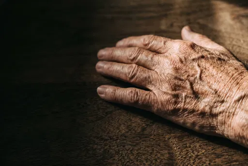 Elderly Wrinkled Hand on Dark Wood