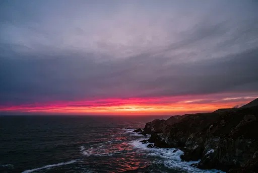 Vibrant Coastal Sunset Under Overcast Clouds