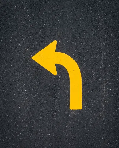 Yellow Curved Left Arrow on Dark Asphalt