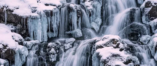 Partially Frozen Winter Waterfall With Blue Icicles